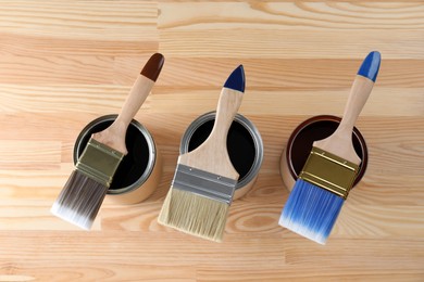 Can with different wood stains and brushes on wooden surface, flat lay