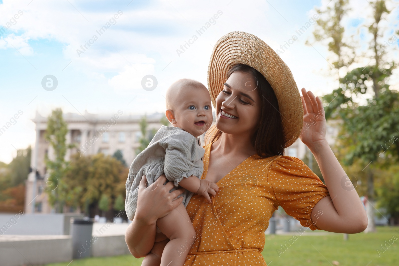Photo of Happy mother with adorable baby walking on sunny day, space for text