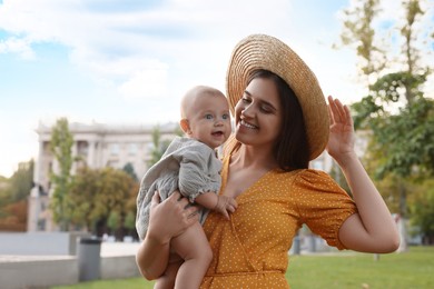 Happy mother with adorable baby walking on sunny day, space for text