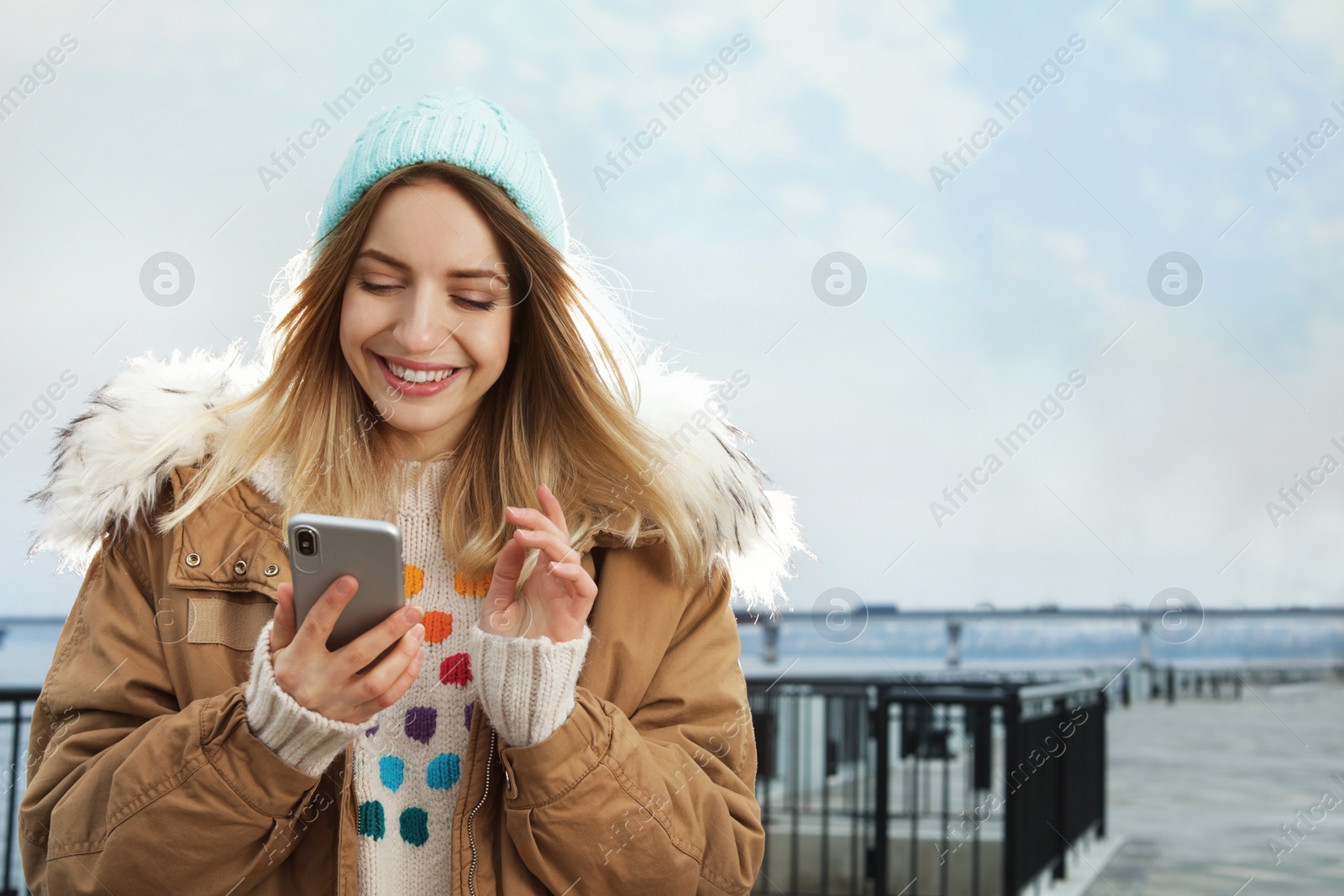 Photo of Young woman using mobile phone outdoors. Space for text