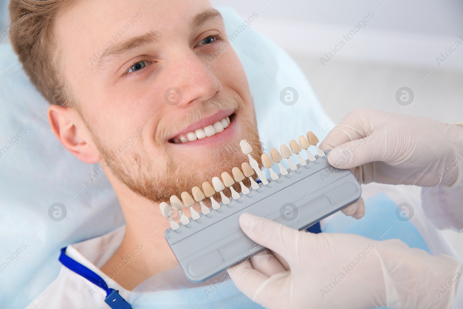 Photo of Dentist selecting patient's teeth color with palette in clinic