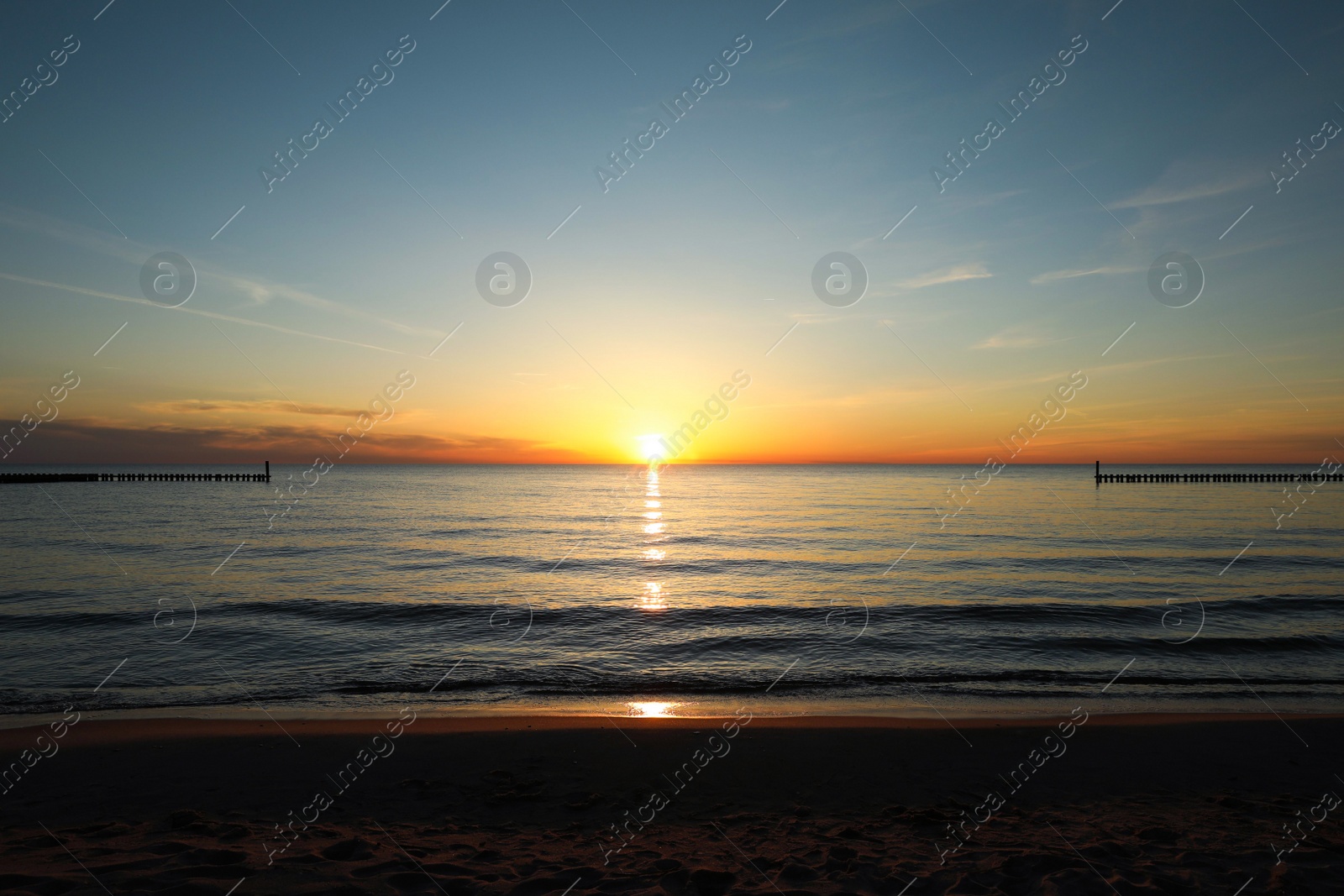 Photo of Picturesque view of sandy beach and sea at sunset