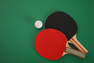 Photo of Rackets and ball on green background, flat lay. Ping pong