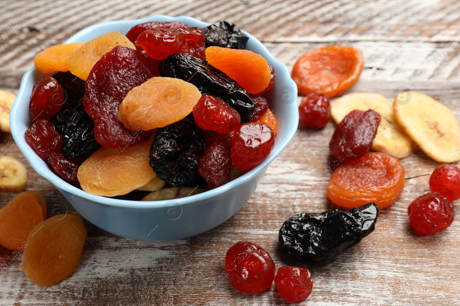 Photo of Mix of delicious dried fruits on wooden table, closeup