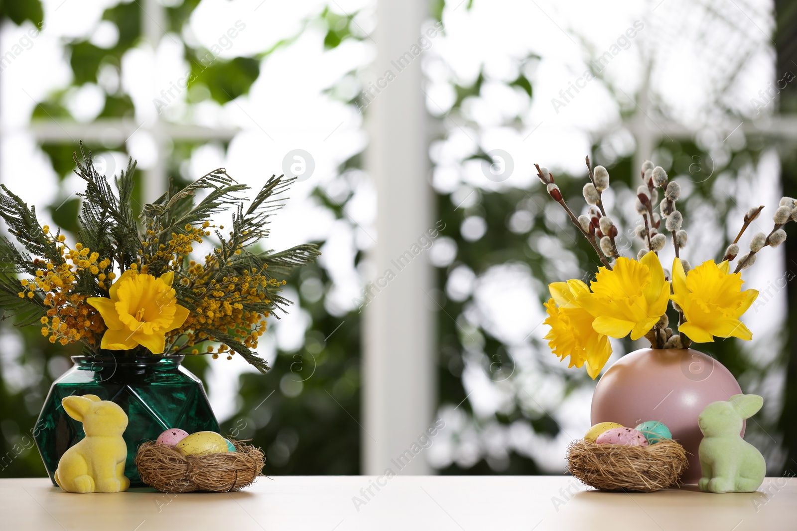 Photo of Festive composition with Easter eggs on table against blurred window