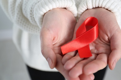 Photo of Woman holding red awareness ribbon, closeup. World AIDS disease day