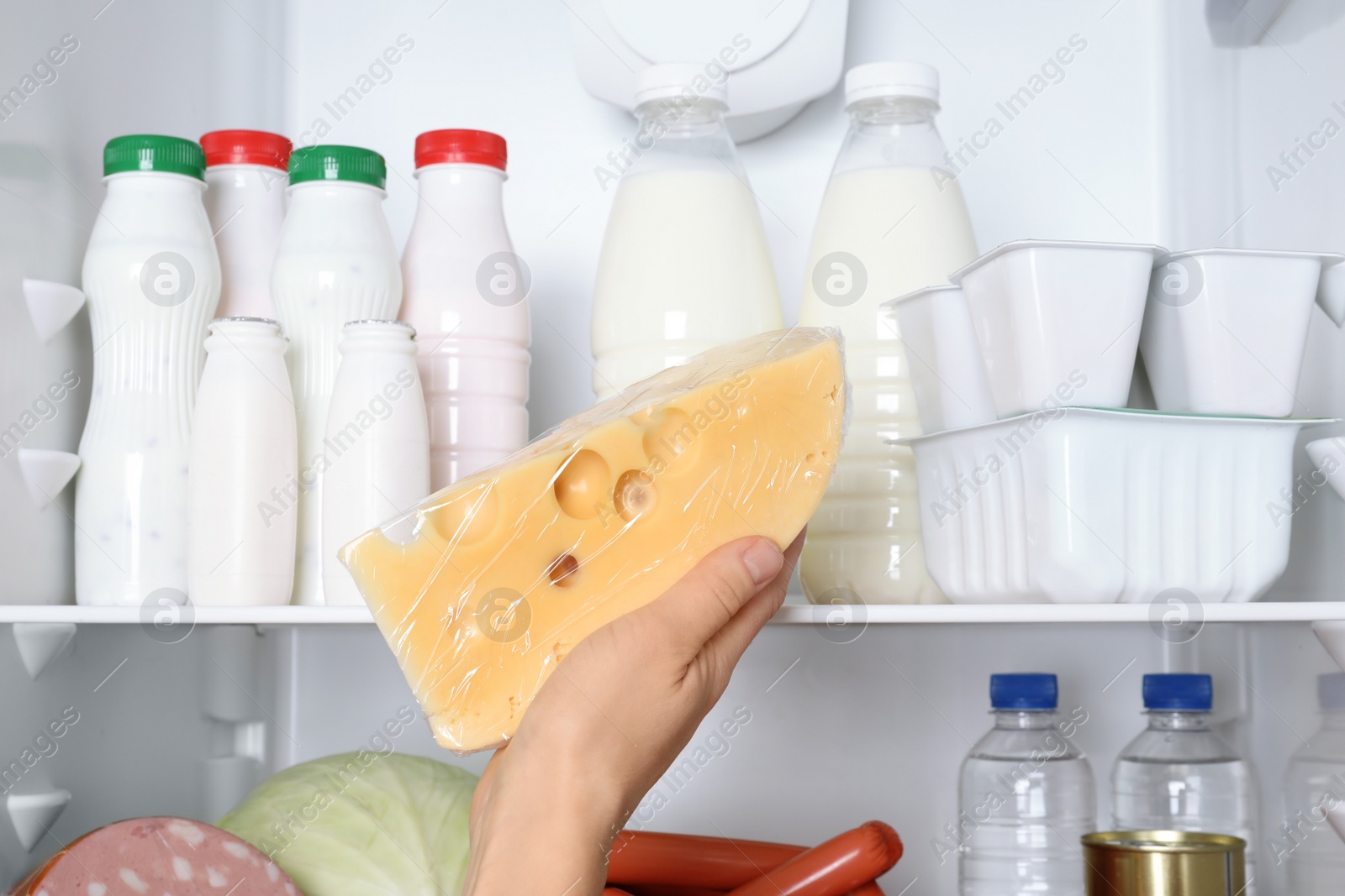 Photo of Woman taking tasty cheese from refrigerator, closeup