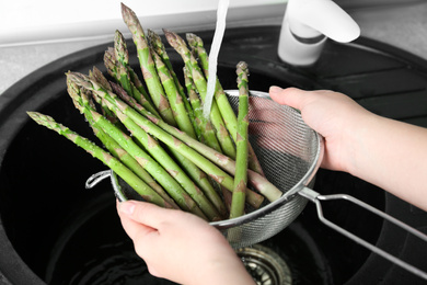 Photo of Woman washing fresh raw asparagus over sink, closeup