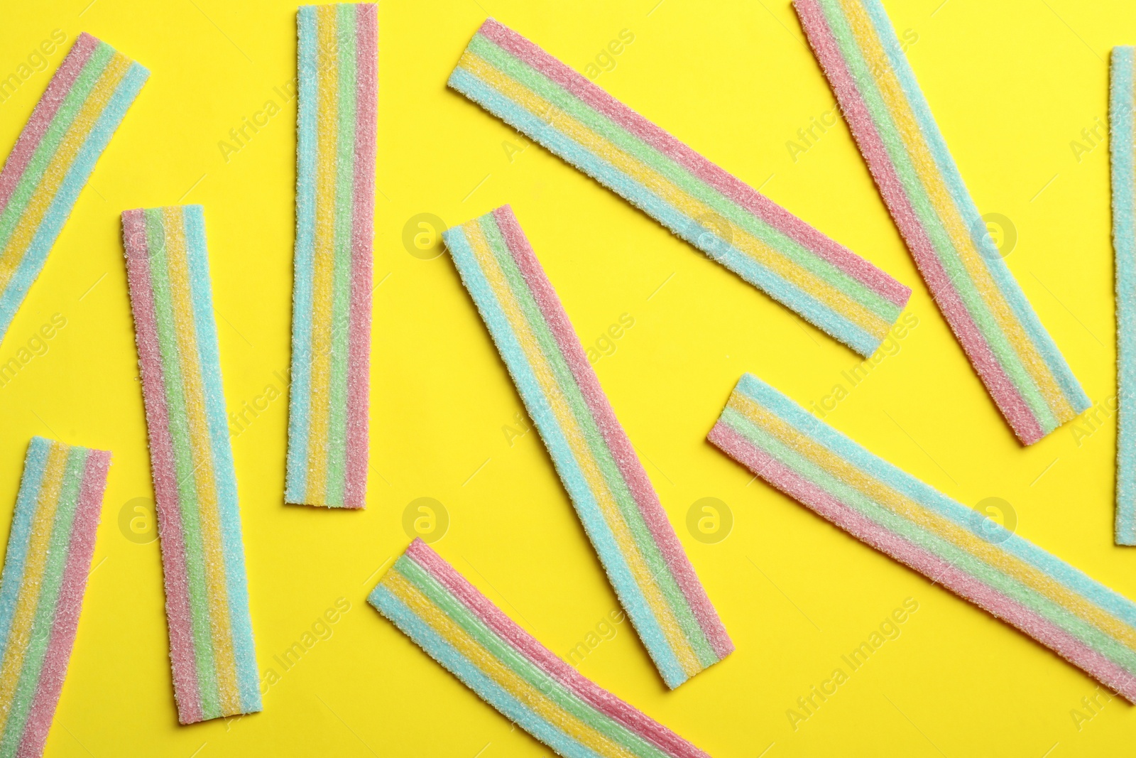 Photo of Delicious gummy candies on yellow background, flat lay