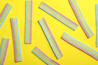 Delicious gummy candies on yellow background, flat lay