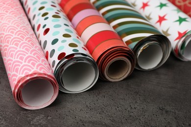 Photo of Different colorful wrapping paper rolls on grey table, closeup