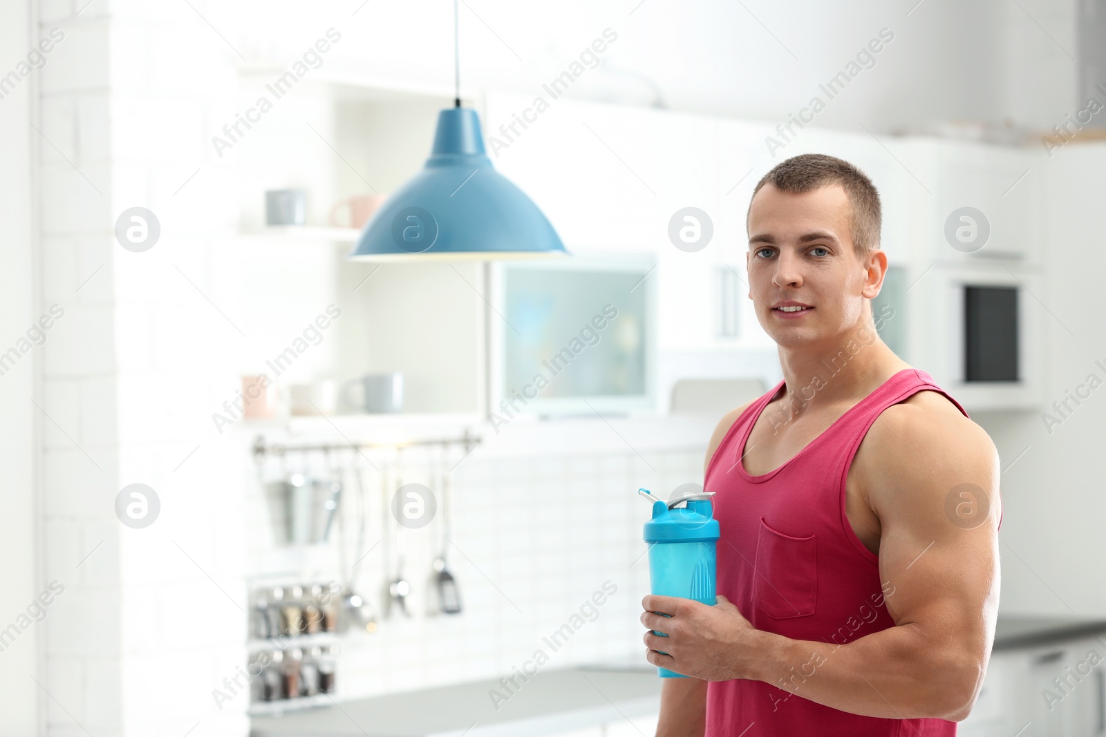 Photo of Athletic young man with protein shake in kitchen