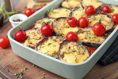 Photo of Baked eggplant with tomatoes and cheese in dishware on table, closeup