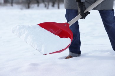 Photo of Man removing snow with shovel outdoors, closeup