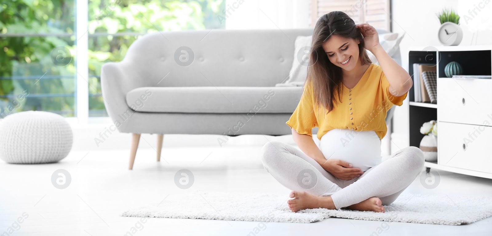 Image of Happy pregnant woman sitting on floor at home, space for text. Banner design