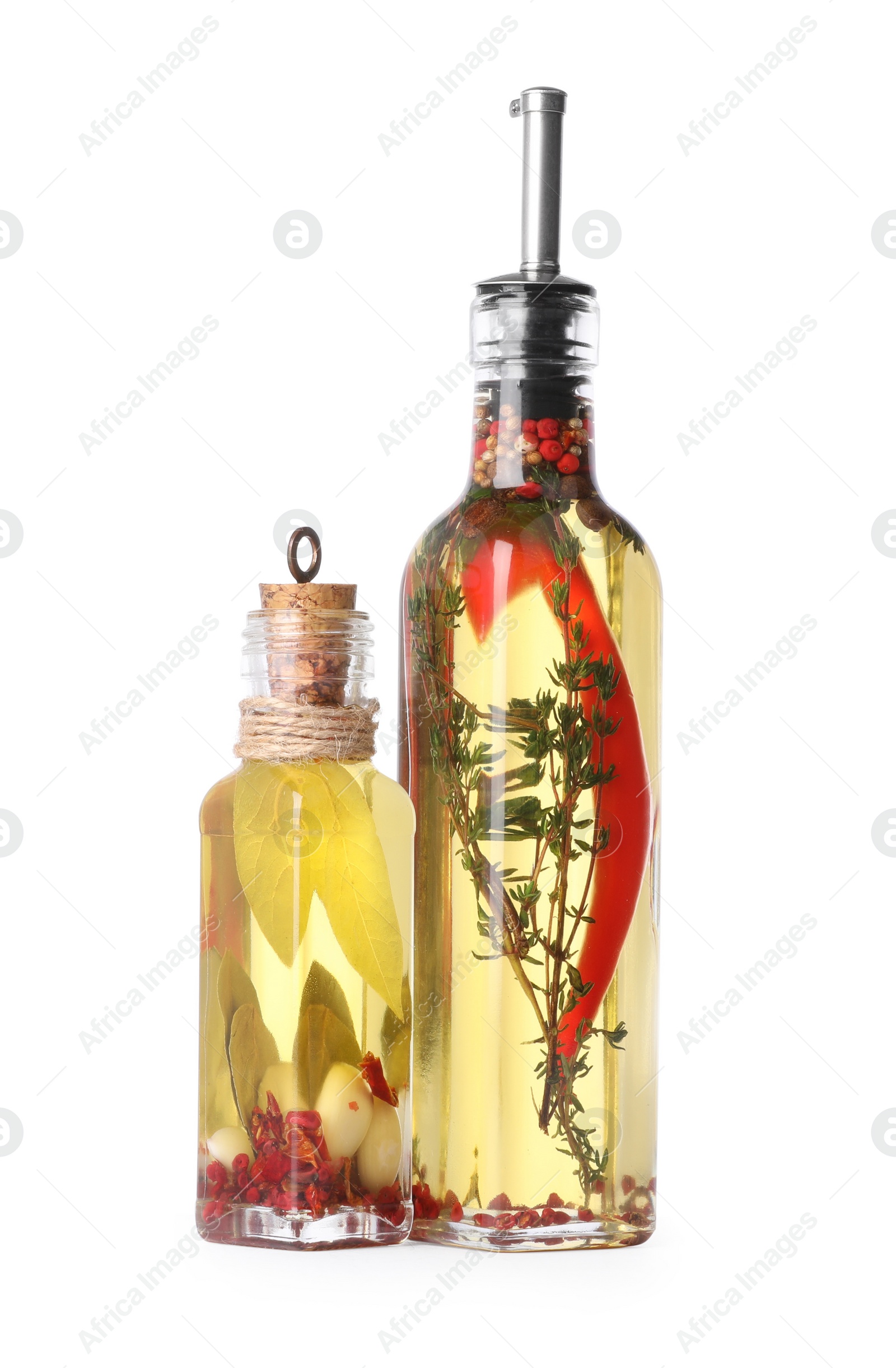 Photo of Glass bottles of cooking oil with spices and herbs on white background