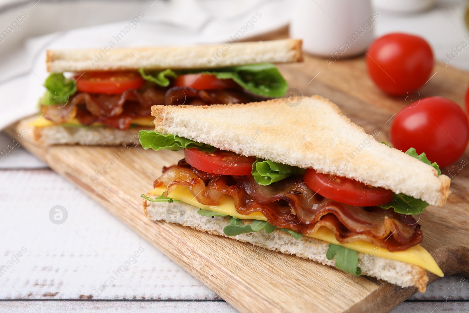 Photo of Delicious sandwiches with fried bacon on wooden rustic table, closeup