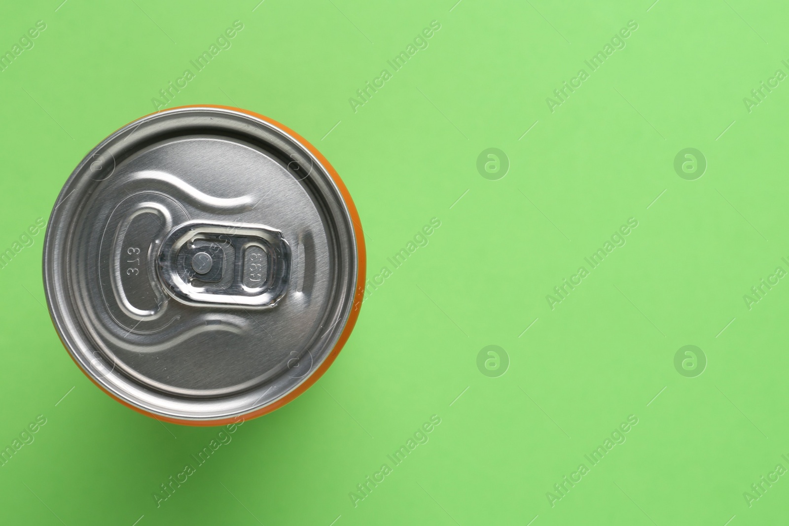 Photo of Energy drink in can on green background, top view. Space for text