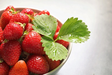 Photo of Bowl with ripe strawberries on grey background, closeup