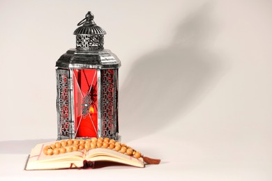 Photo of Arabic lantern, Quran and misbaha on light background. Space for text