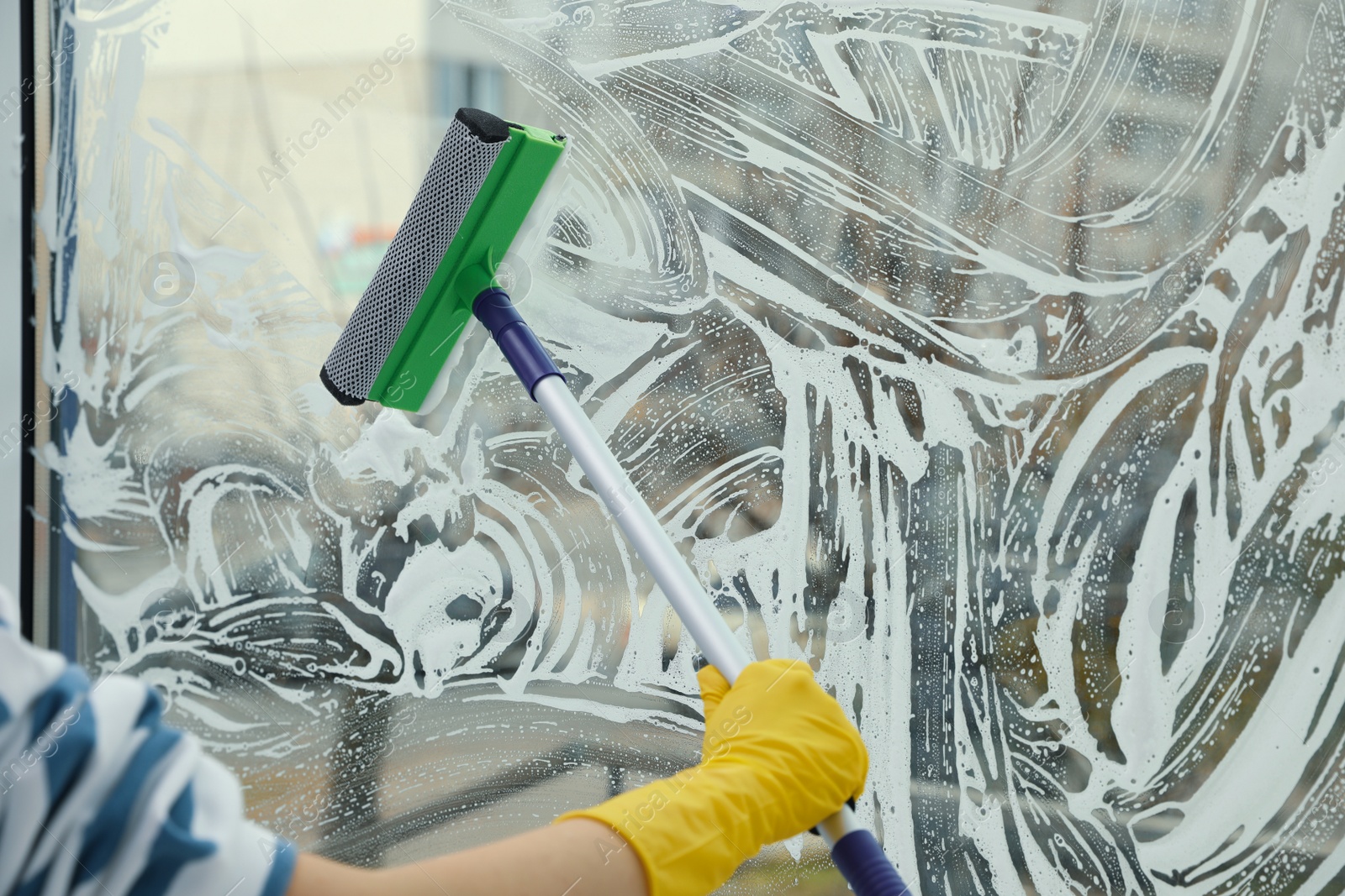 Photo of Woman cleaning window with squeegee at home, closeup. Space for text