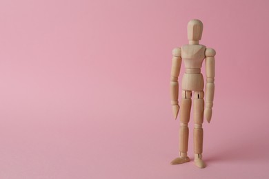 Photo of Wooden human model on pink background, space for text. Mini mannequin