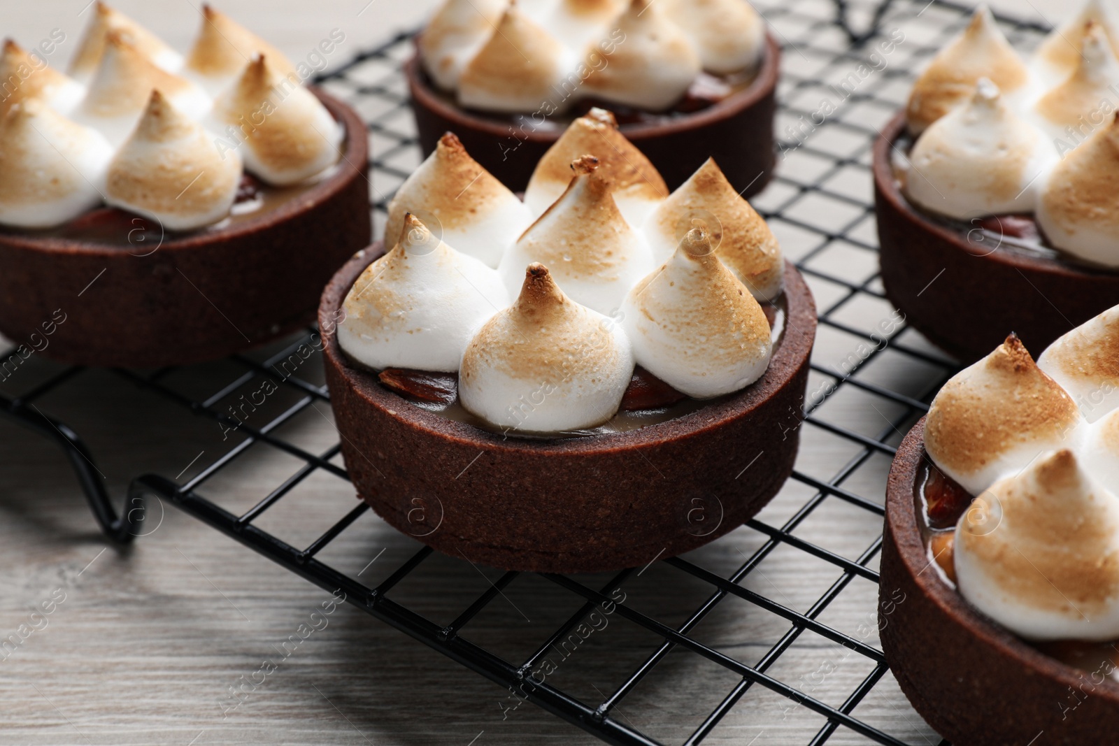 Photo of Delicious salted caramel chocolate tarts on light wooden table, closeup