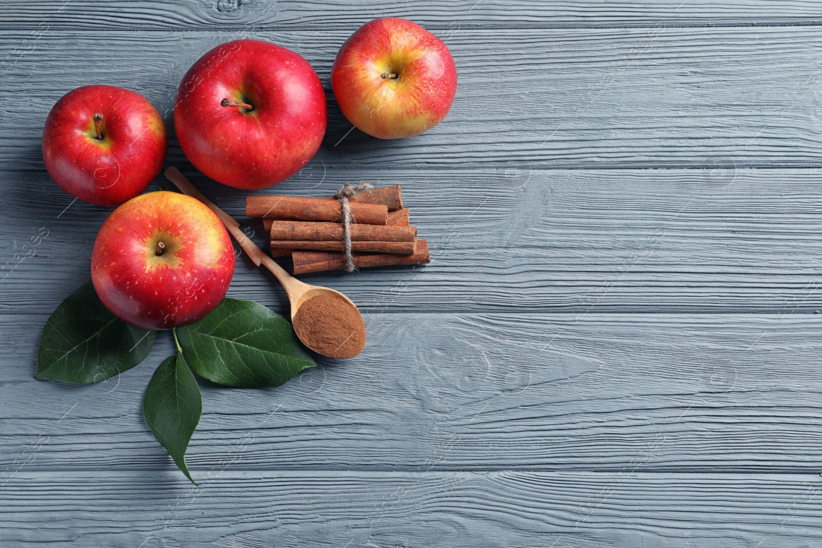 Photo of Fresh apples with cinnamon sticks and powder on wooden table, top view