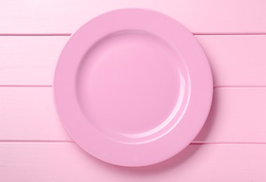 Empty ceramic plate on pink wooden table, top view