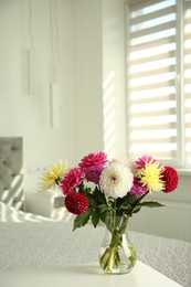 Photo of Bouquet of beautiful Dahlia flowers in vase on white table indoors. Space for text