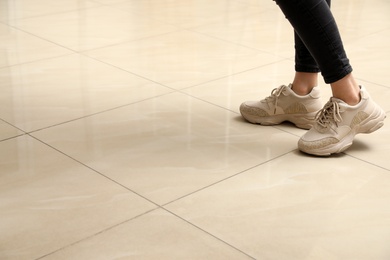 Woman standing on ceramic floor, closeup. Space for text