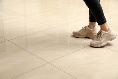 Photo of Woman standing on ceramic floor, closeup. Space for text