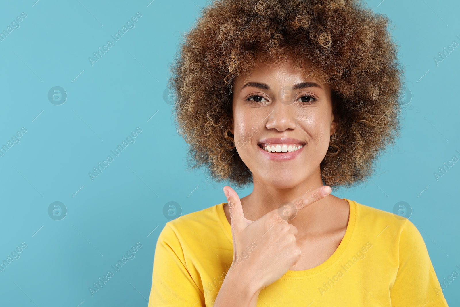 Photo of Woman showing her clean teeth and smiling on light blue background, space for text
