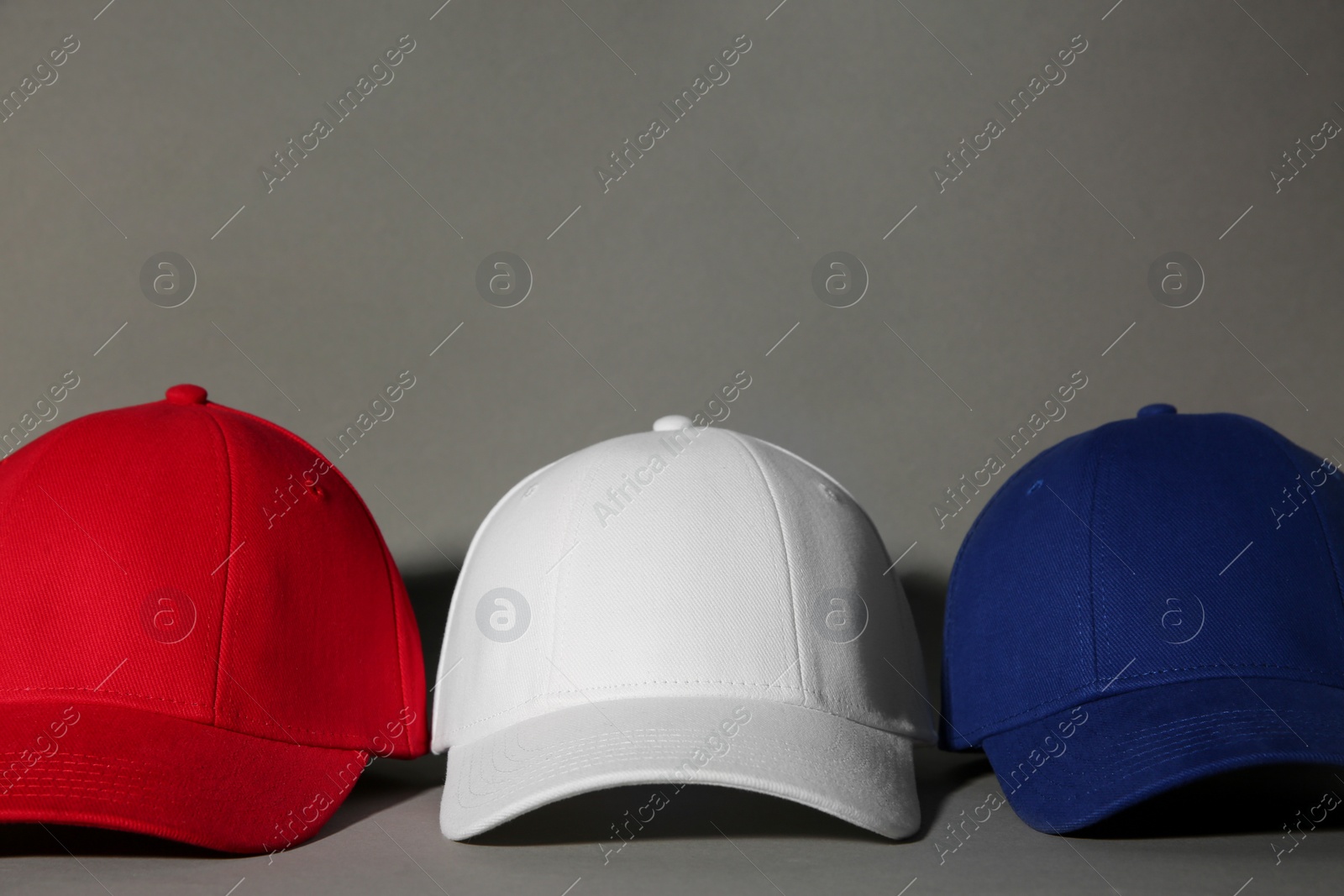 Photo of Stylish color baseball caps on grey background