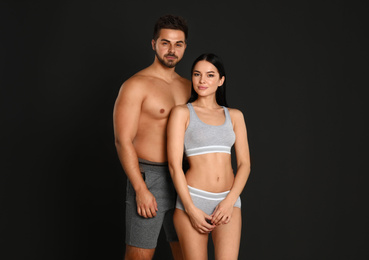 Photo of Young couple in grey sportive underwear on black background