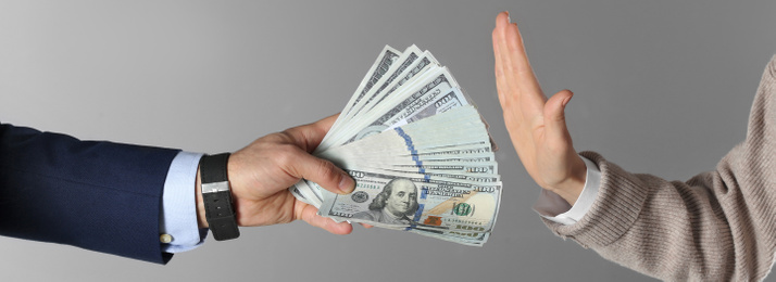 Image of Woman refusing to take bribe on grey background, closeup. Banner design