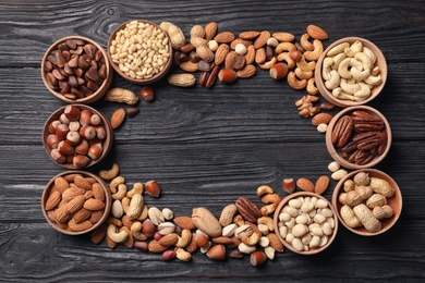 Frame made of organic mixed nuts on wooden background, top view. Space for text