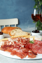 Photo of Tasty prosciutto served on light grey marble table