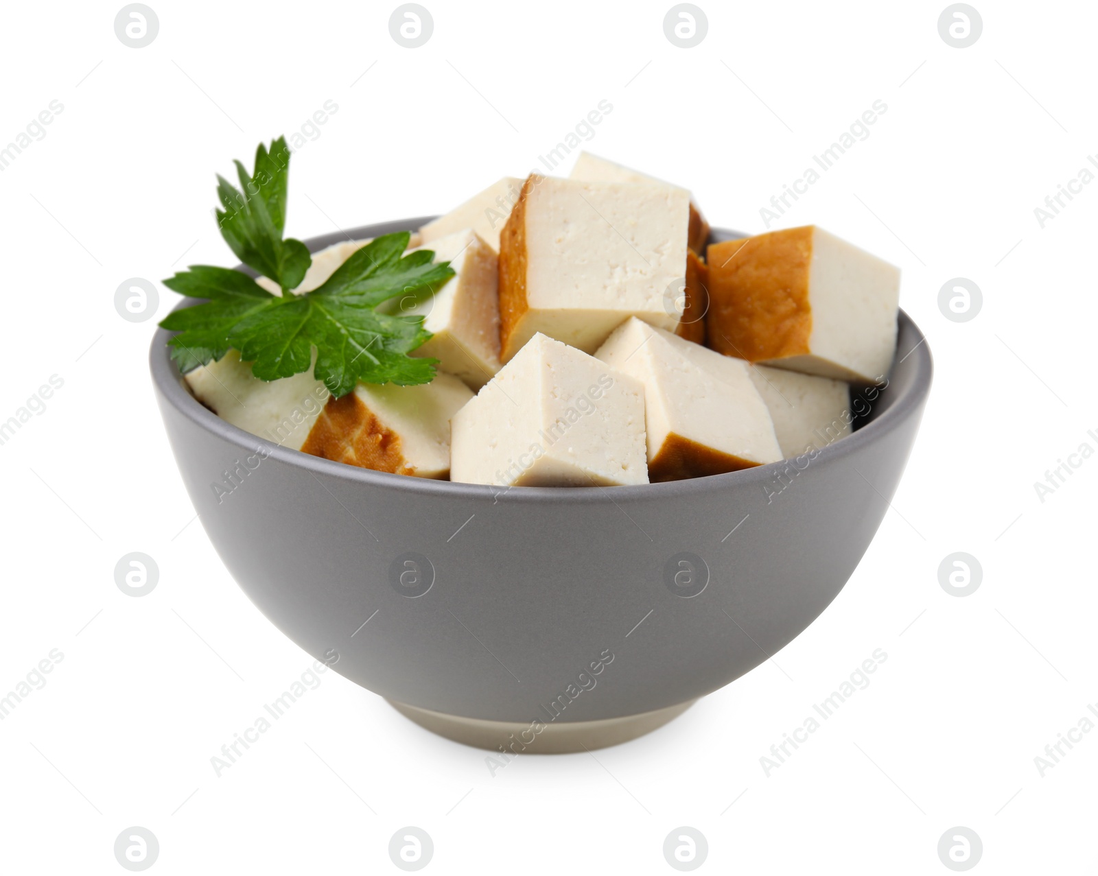 Photo of Bowl of delicious smoked tofu cubes with parsley isolated on white