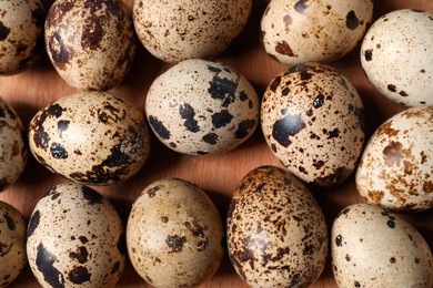 Photo of Many fresh quail eggs on wooden tray, flat lay