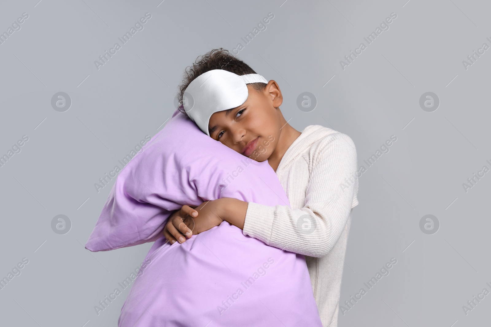 Photo of Boy with pillow and sleep mask on grey background. Insomnia problem