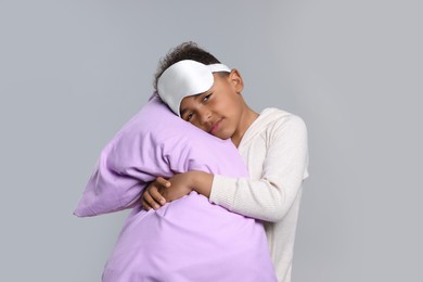 Photo of Boy with pillow and sleep mask on grey background. Insomnia problem