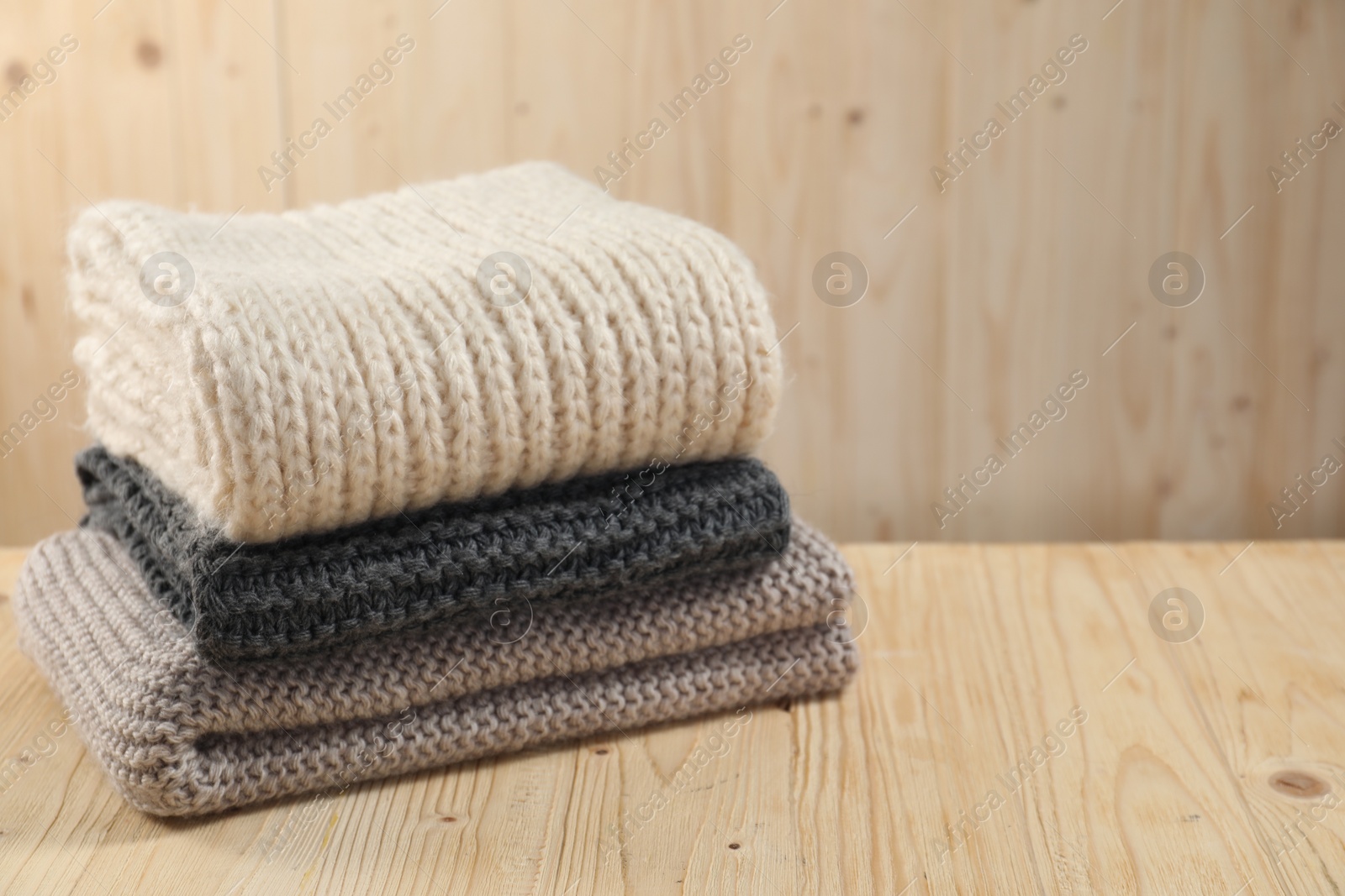 Photo of Knitted scarfs on wooden table, space for text