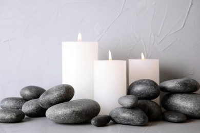 Photo of Zen stones and lighted candles on table against light background