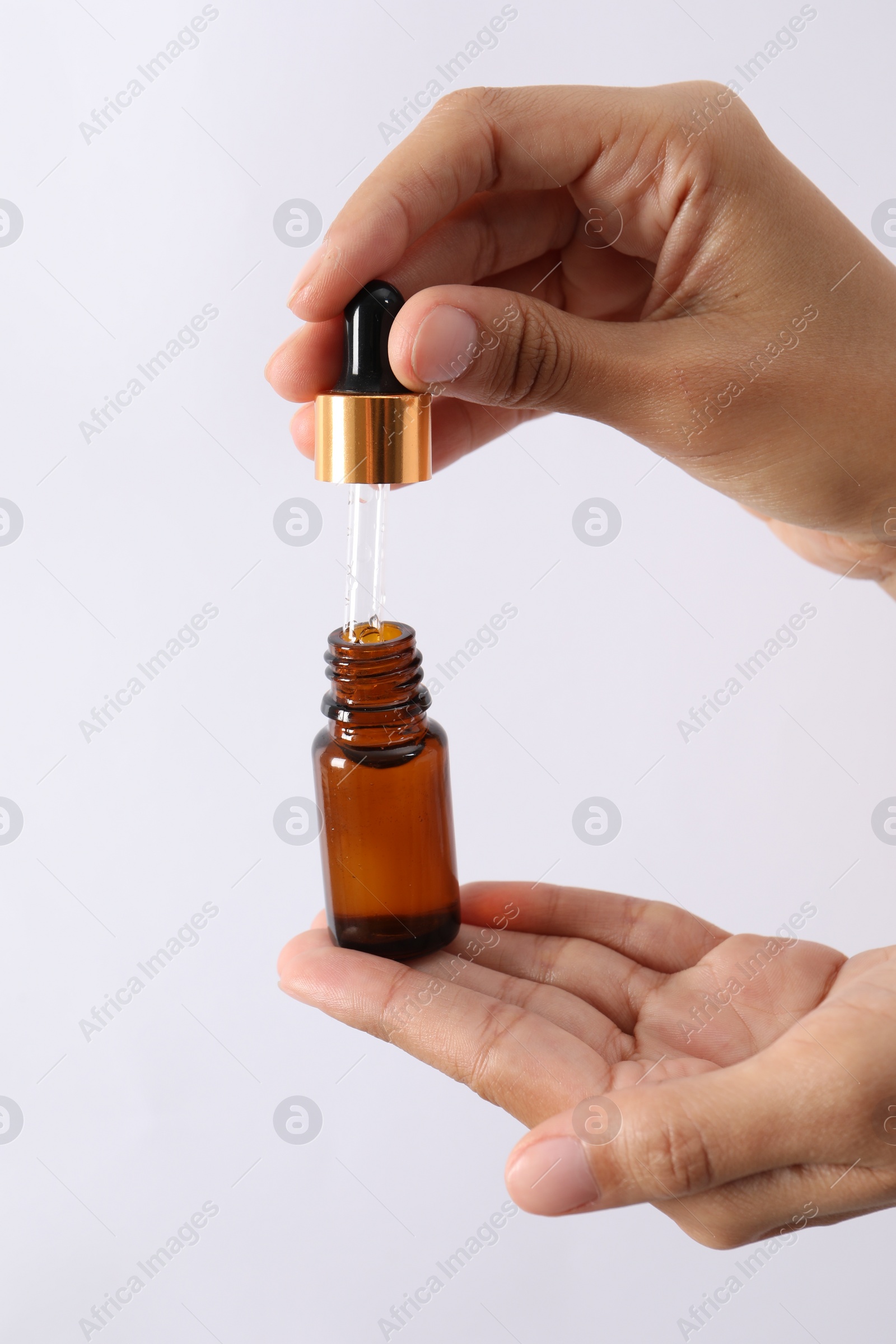 Photo of Woman with bottle of cosmetic serum and dropper on white background, closeup