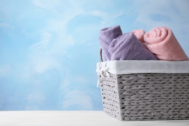 Photo of Basket with soft bath towels on table. Space for text