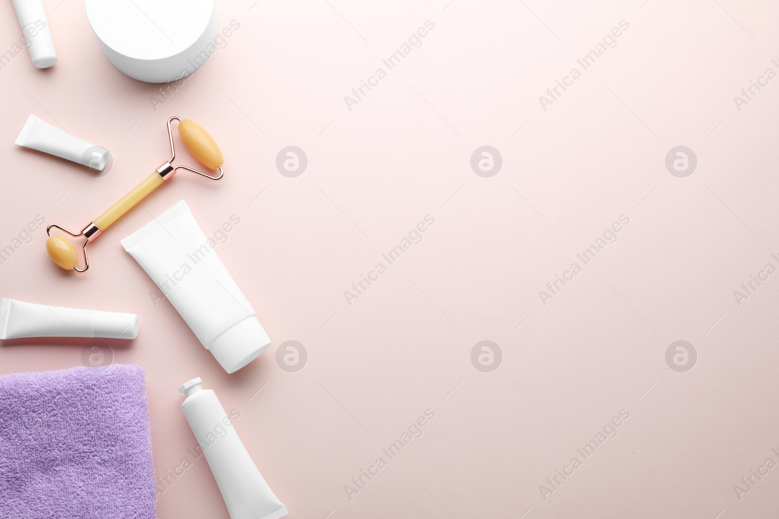 Photo of Natural face roller, cosmetic products and towel on pink background, flat lay. Space for text