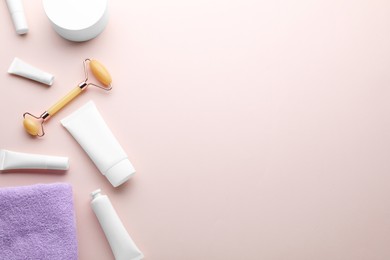 Natural face roller, cosmetic products and towel on pink background, flat lay. Space for text