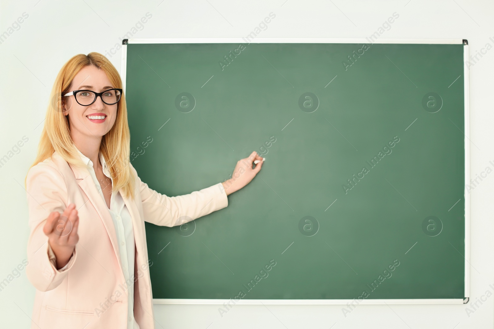 Photo of English teacher near green chalkboard at lesson