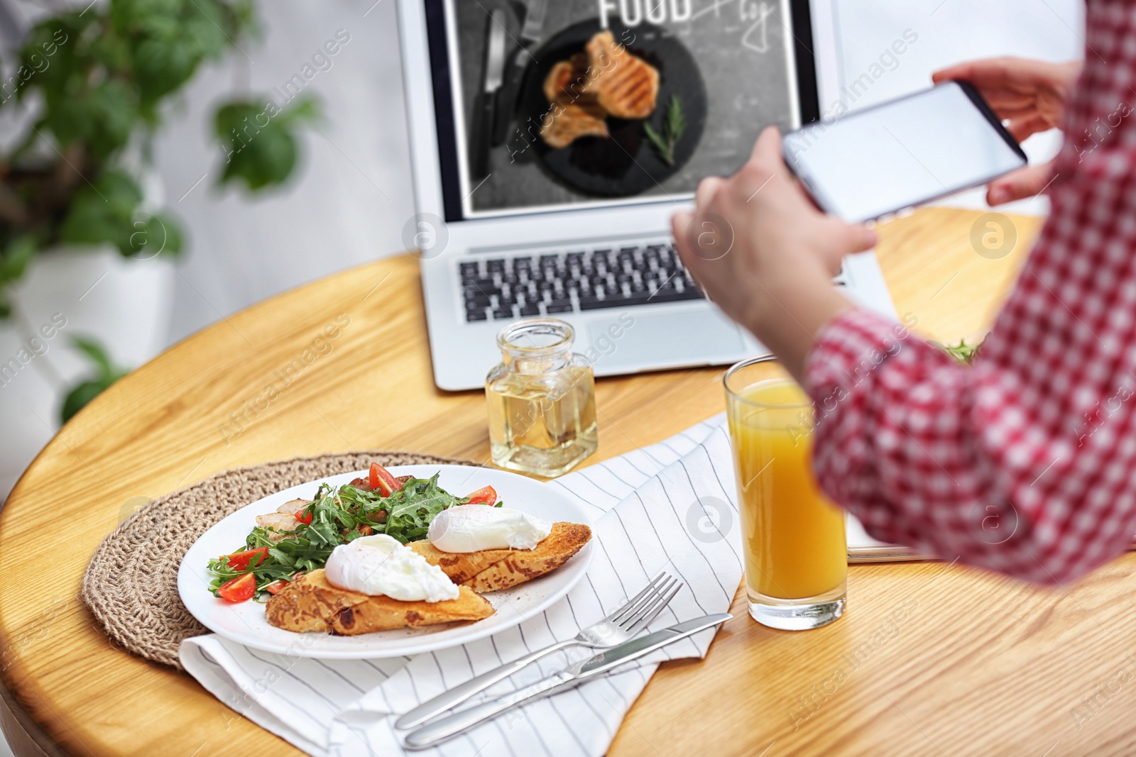 Photo of Food blogger taking photo of her lunch at wooden table indoors, closeup